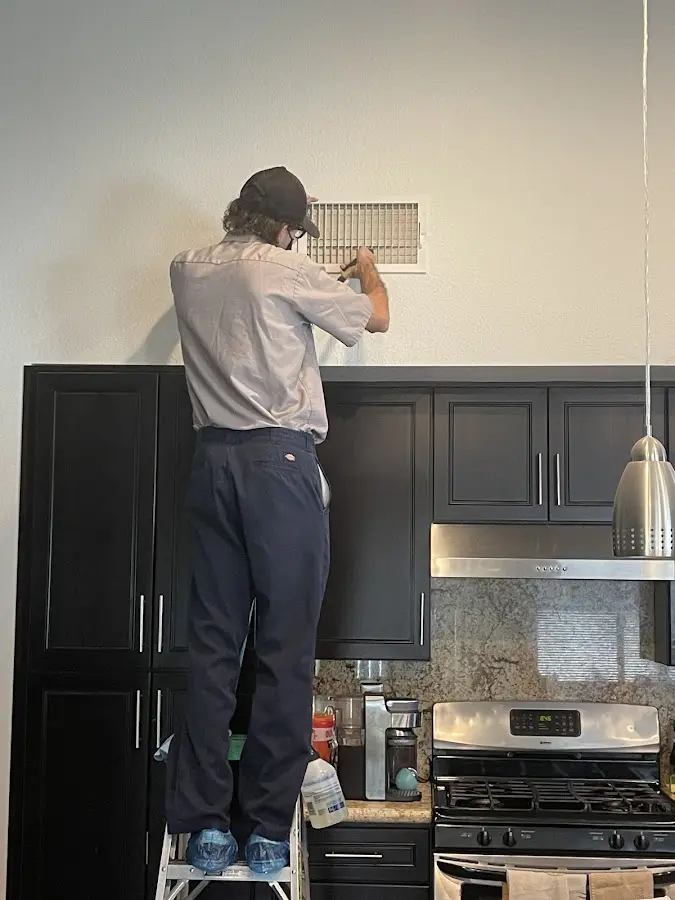 Technician inspecting an air vent during HVAC service in Salinas
